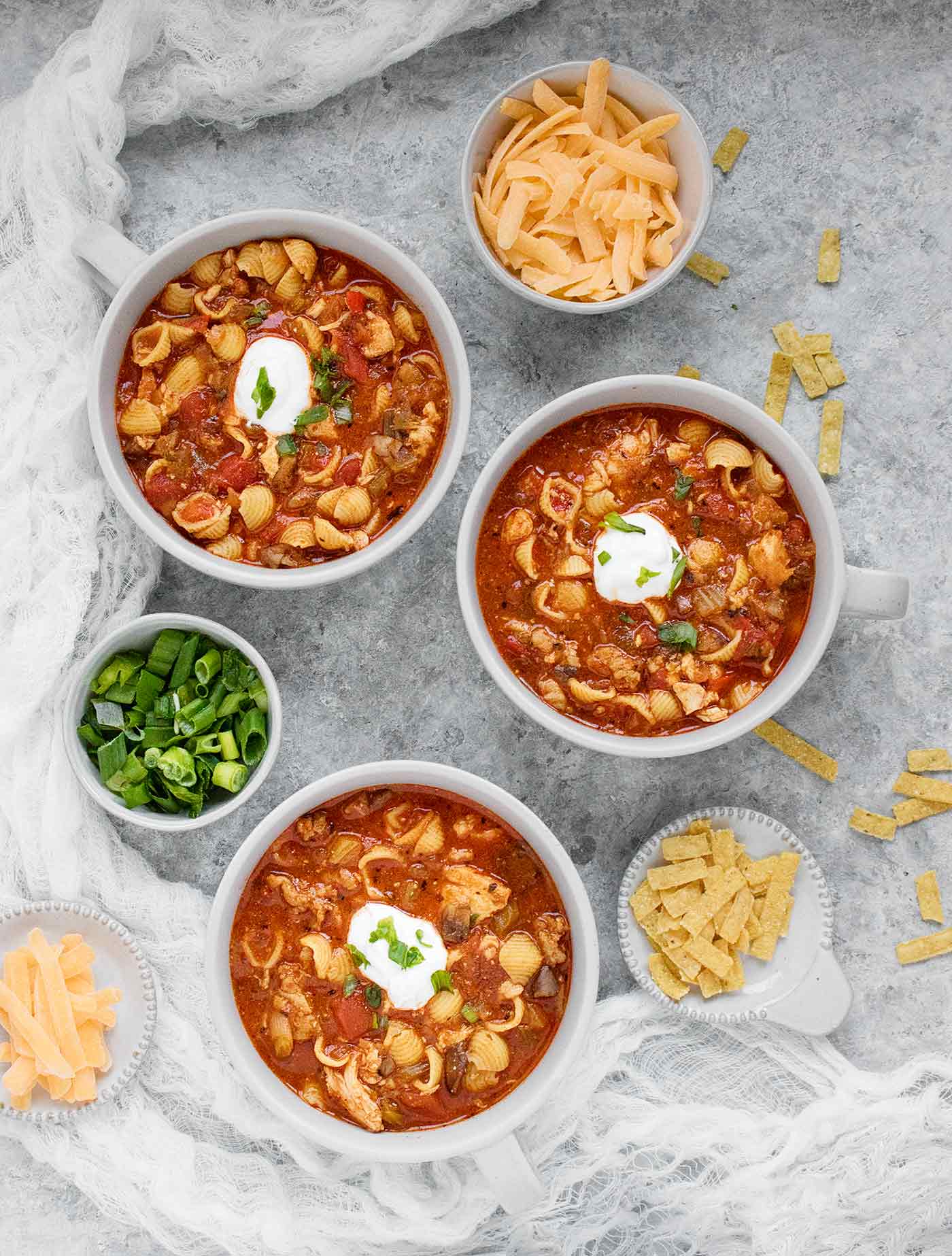 Three bowls of chicken chili soup, with toppings on the side