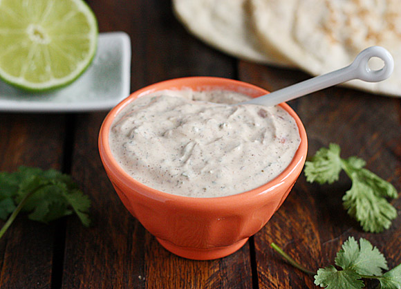 Close up of fish taco sauce in an orange bowl with a white spoon