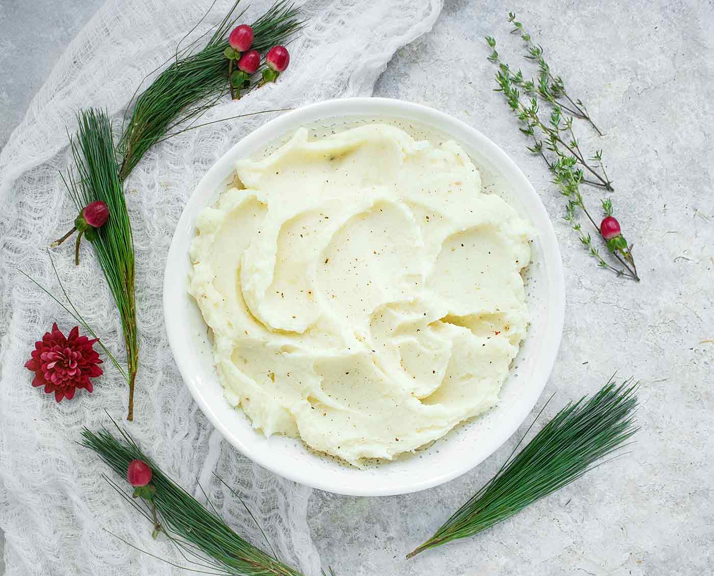 A large, white serving bowl with Roasted Garlic Mashed Potatoes