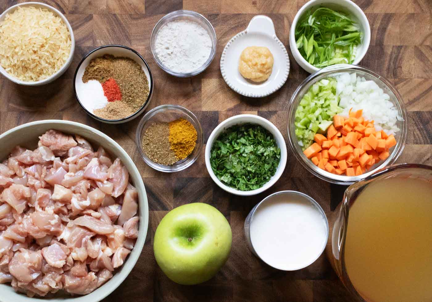 Ingredients for Mulligatawny Soup measured into bowl and arranged on a wooden board.
