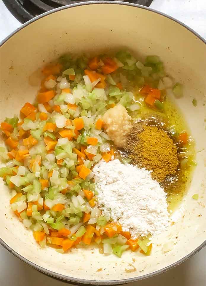 Adding the spices and flour to the vegetables.