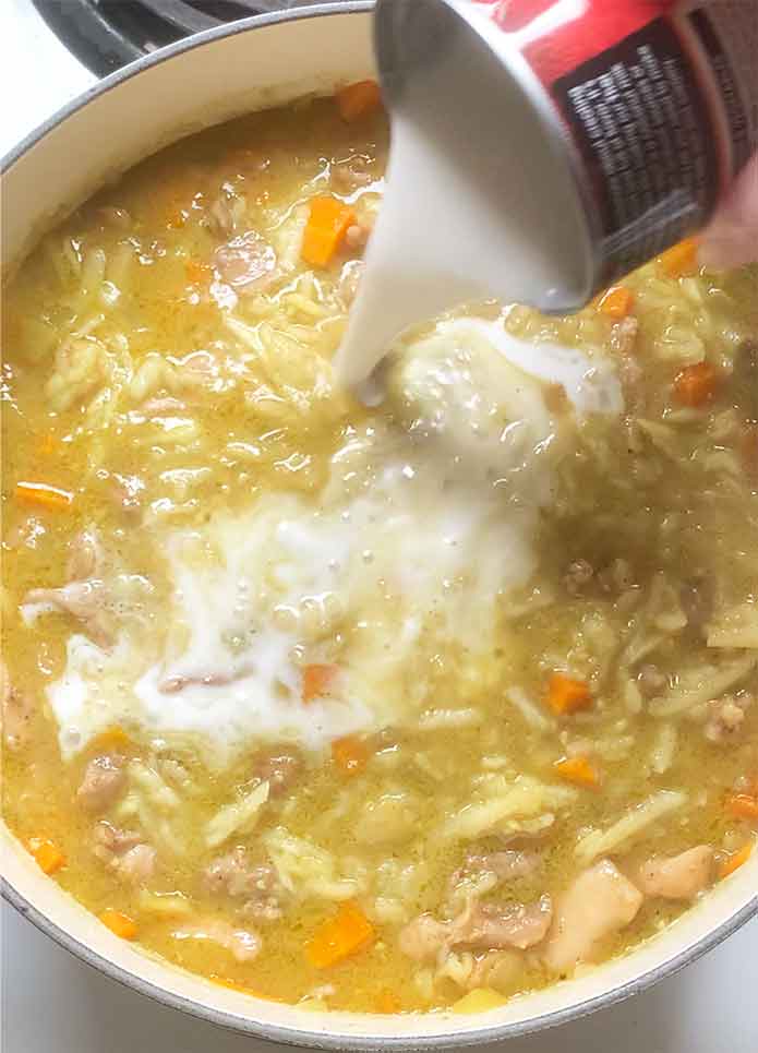 Pouring in the coconut milk into the soup.