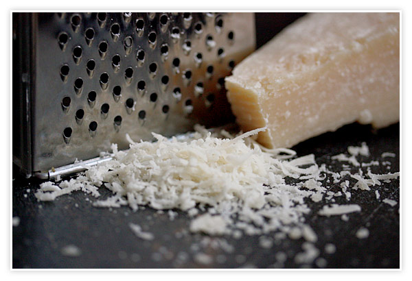 Close-up of grated cheese from a parmesan cheese block.