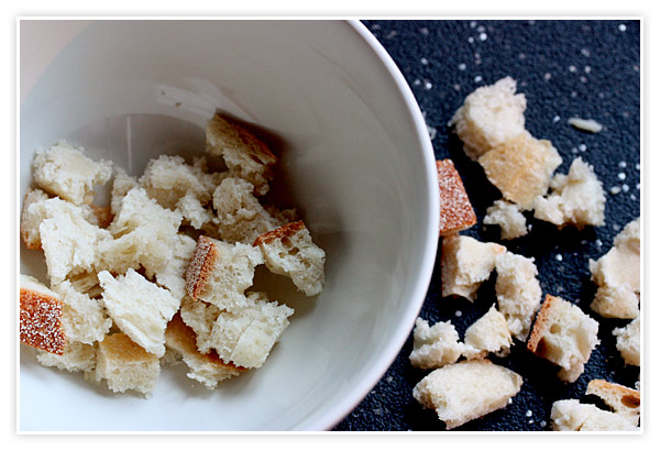 A white soup bowl lined with pieces of bread.