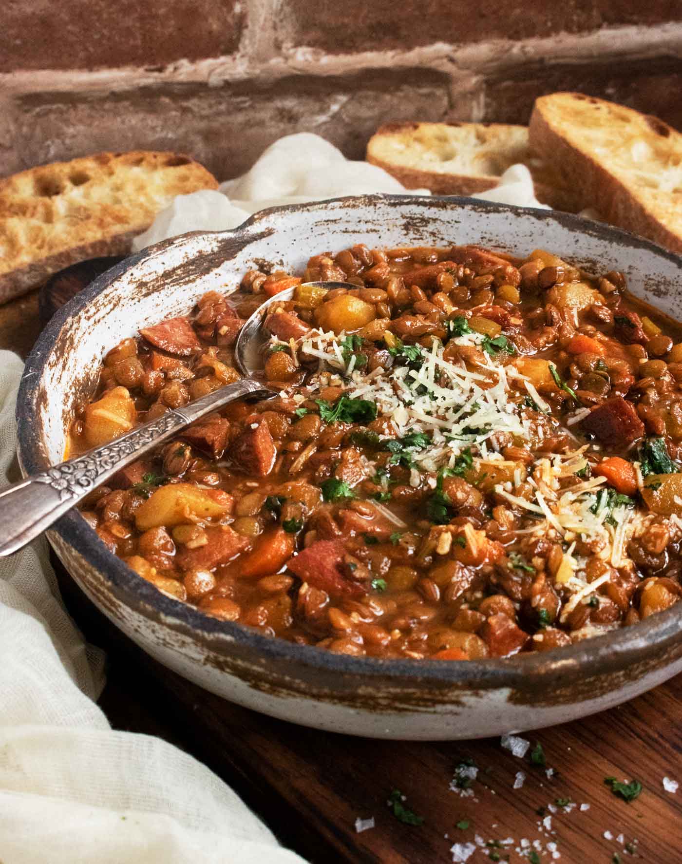 Side-angled view of a bowl of Rustic Lentil Soup on a serving board.