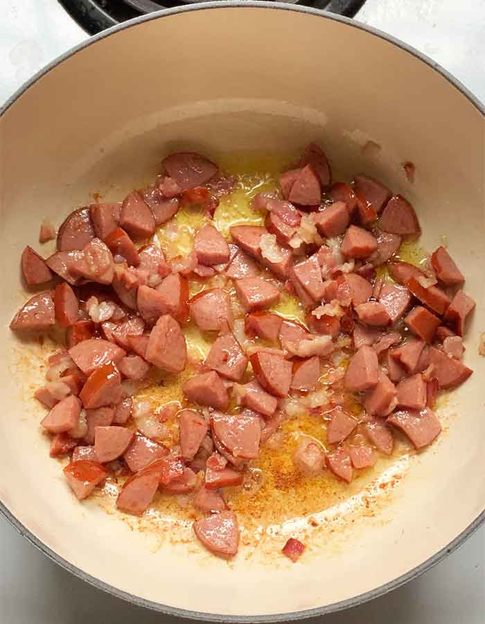 Bacon and smoked sausage cooking in the pot.