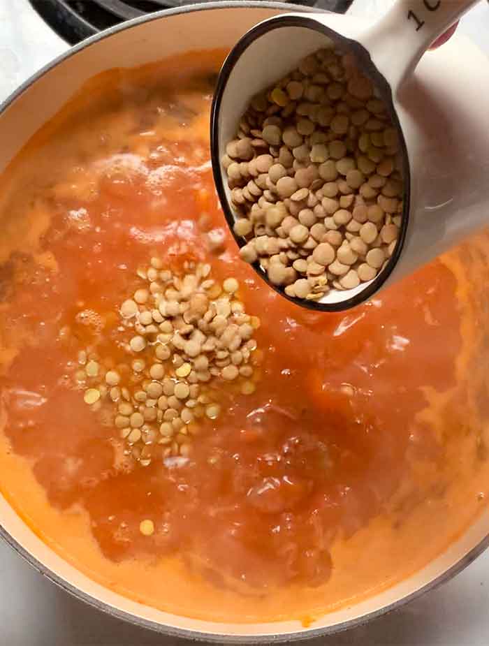 Adding the dried lentils to cook in the soup.