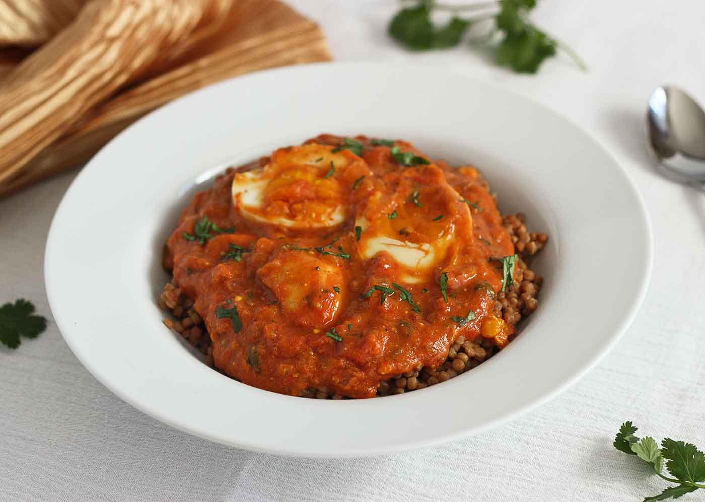 Egg curry in a large white, rimmed bowl.