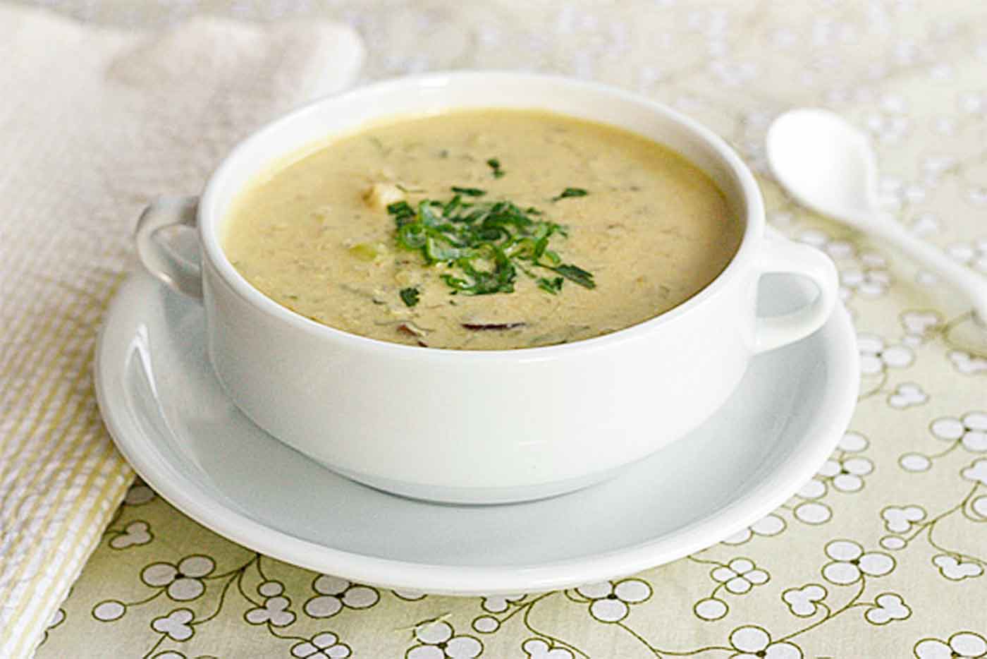 Side-angled view of Tom Kha Gai soup in a white bowl.