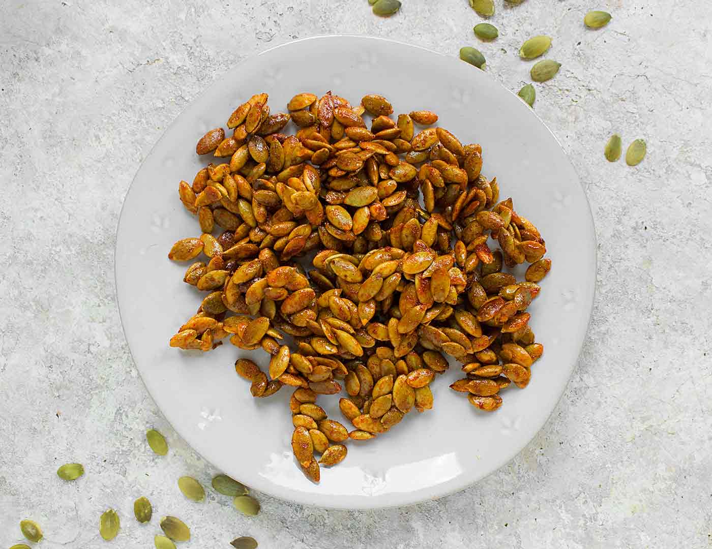 Honey sriracha pumpkin seeds on a white plate