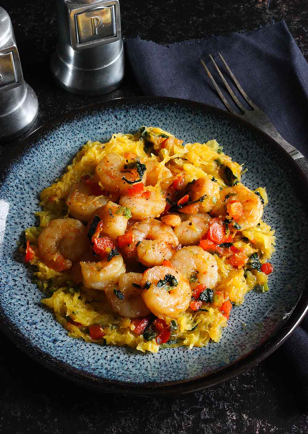 A plate of shrimp and vegetables over spaghetti squash, ready to serve.
