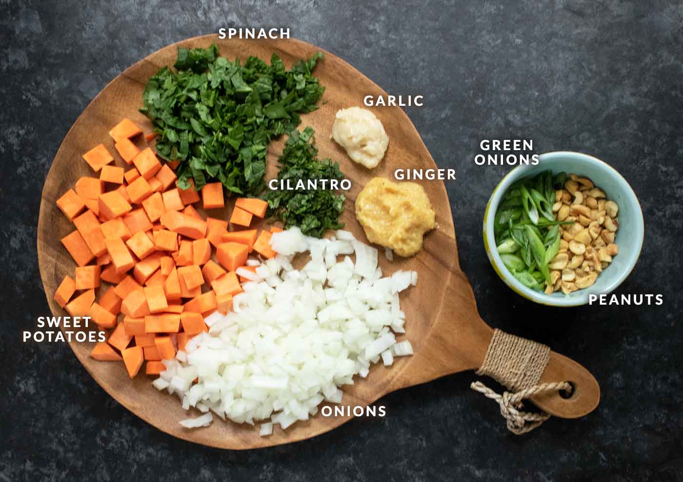 Prepared ingredients for West African Peanut Soup on a wooden serving board.