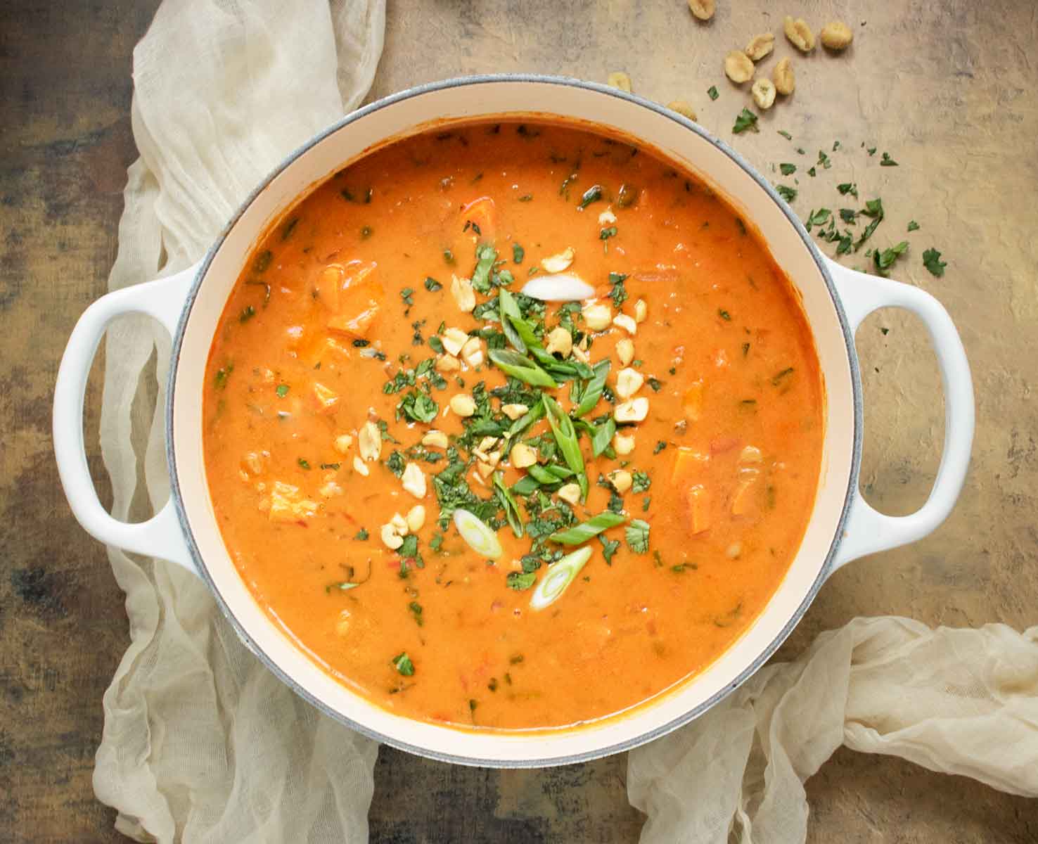Overhead view of a pot of West African Peanut Soup adorned with toppings.