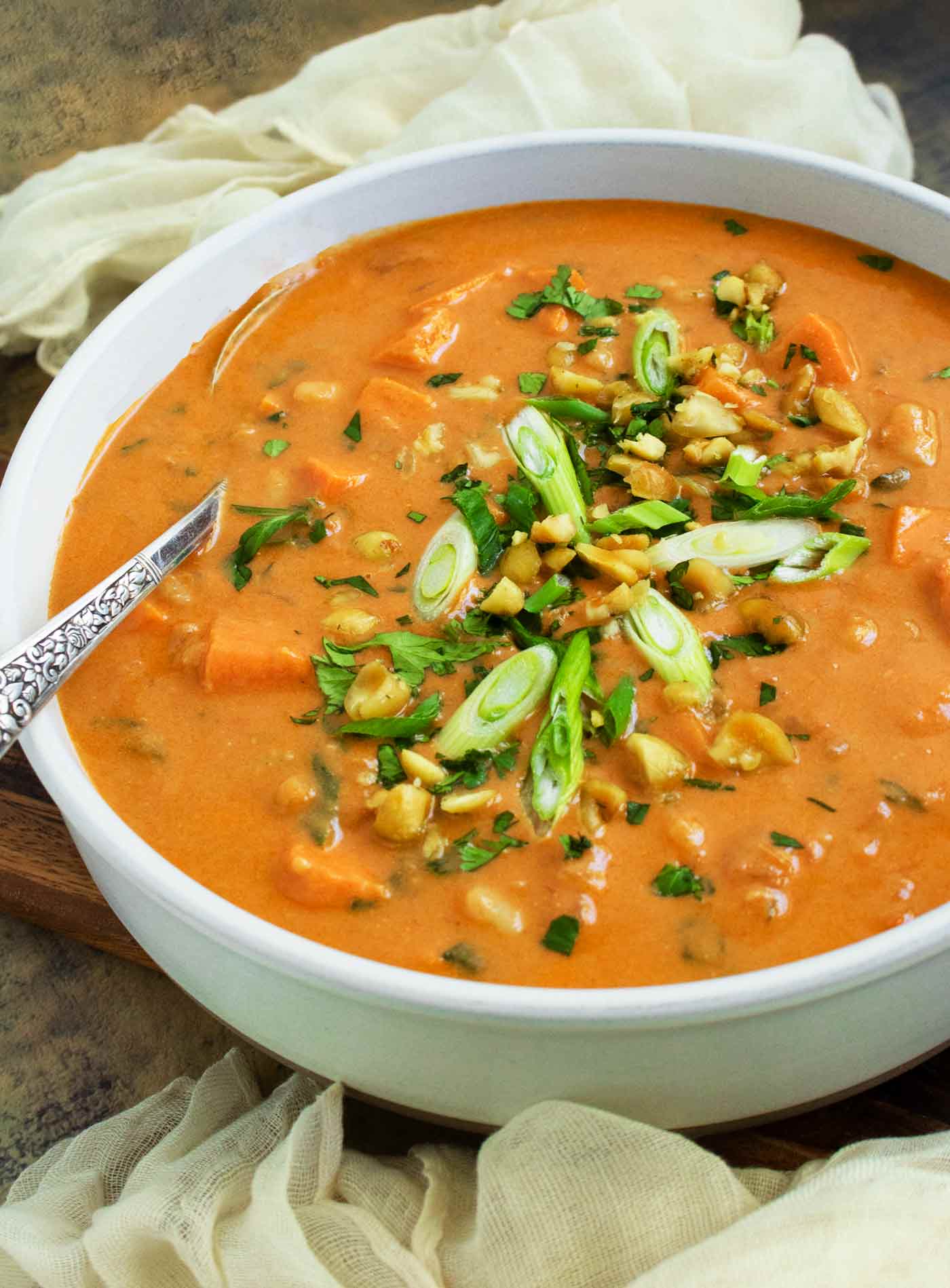 Side angled view of a bowl of West African Peanut Soup with a spoon.