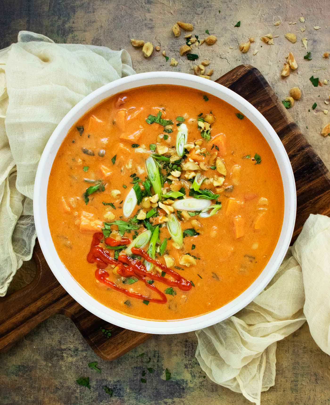 Photo taken from above of a bowl of West African Peanut Soup on a wooden board.