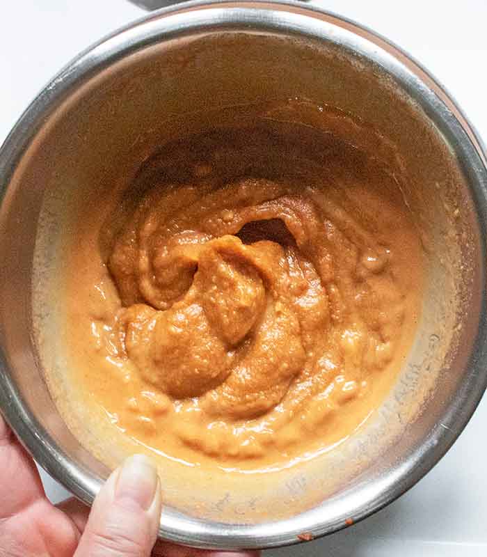 Tempering the peanut butter with the hot soup.