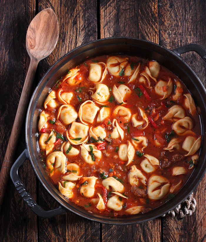 A pot of Italian Tortellini soup on a wooden board