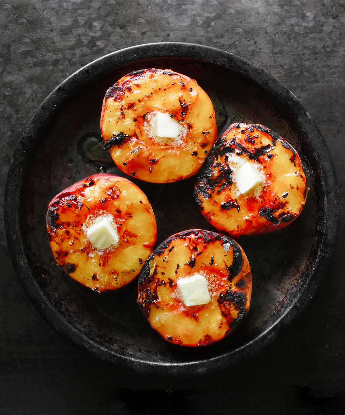 Grilled peaches with a pat of butter, on a tin