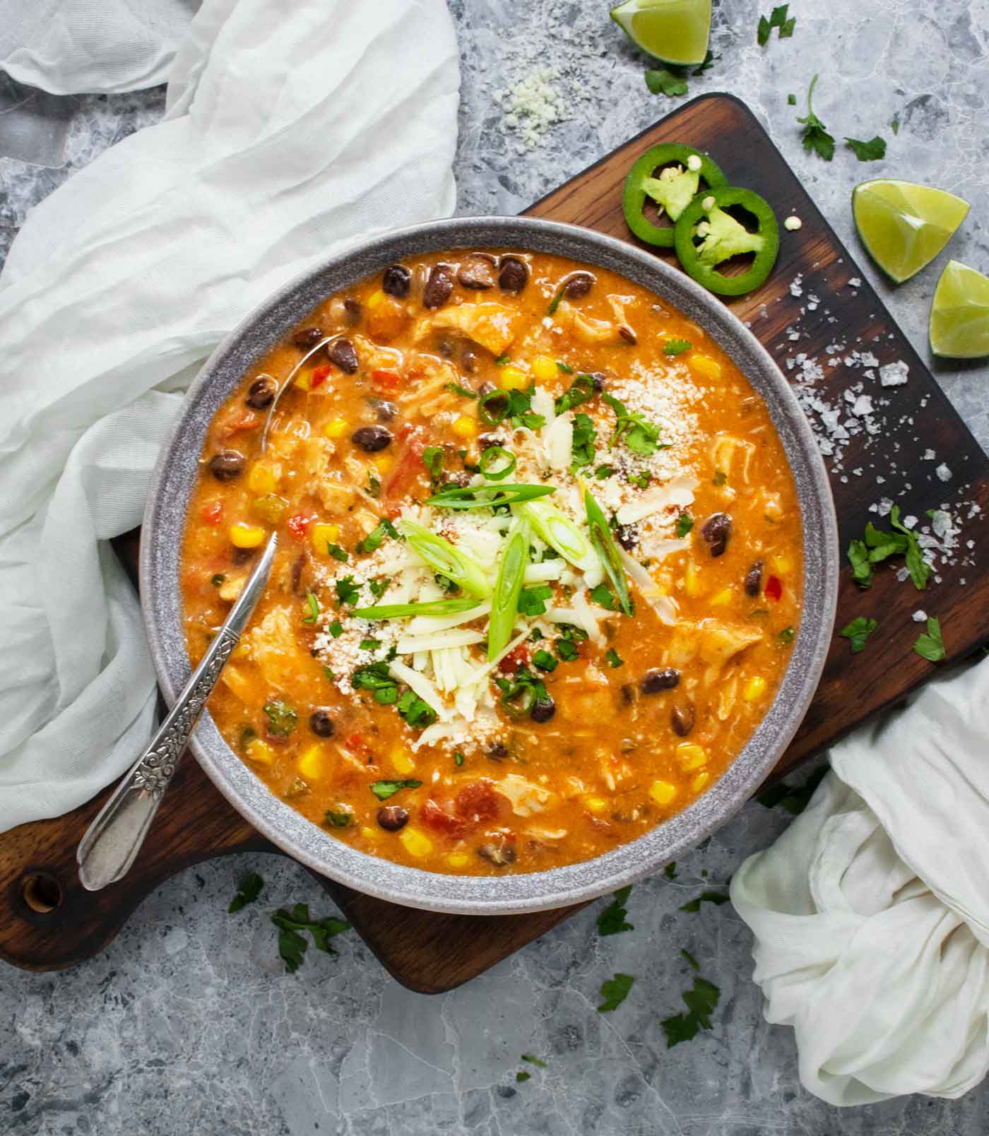 A bowl of Chicken Enchilada Soup on a wooden serving board.