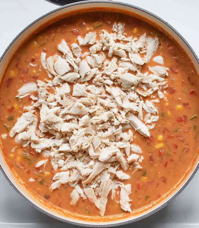 Shredded rotisserie chicken going into the pot.