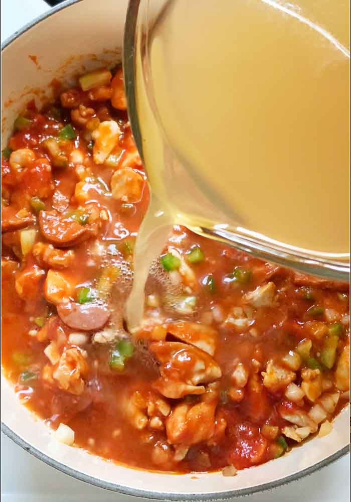 Pouring the chicken broth into the pot.