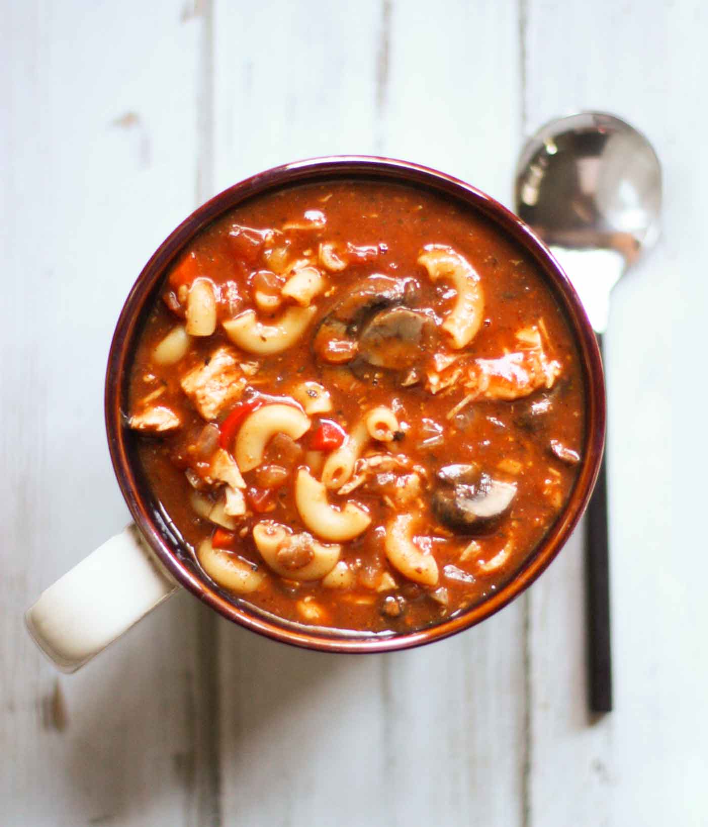 Overhead view of Slow Cooker Chicken Chili Soup in a large mug with a serving spoon.