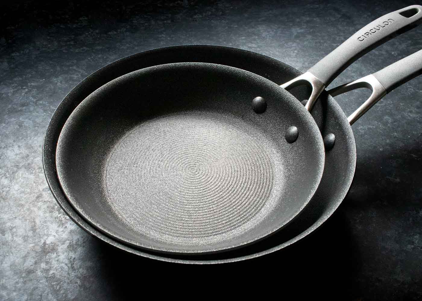 Two Circulon nonstick skillets, the smaller one sitting in the larger one.