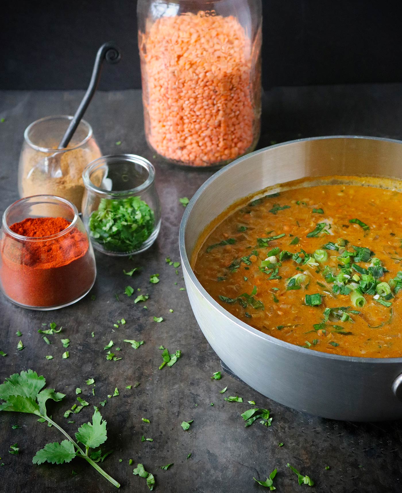 A pot of lentil masala soup, with spice jars