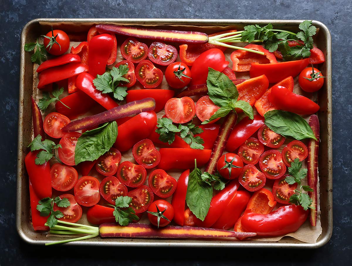 The beautiful red vegetables for Sheet Pan Roasted Red Pepper Tomato Soup spread on a baking sheet.