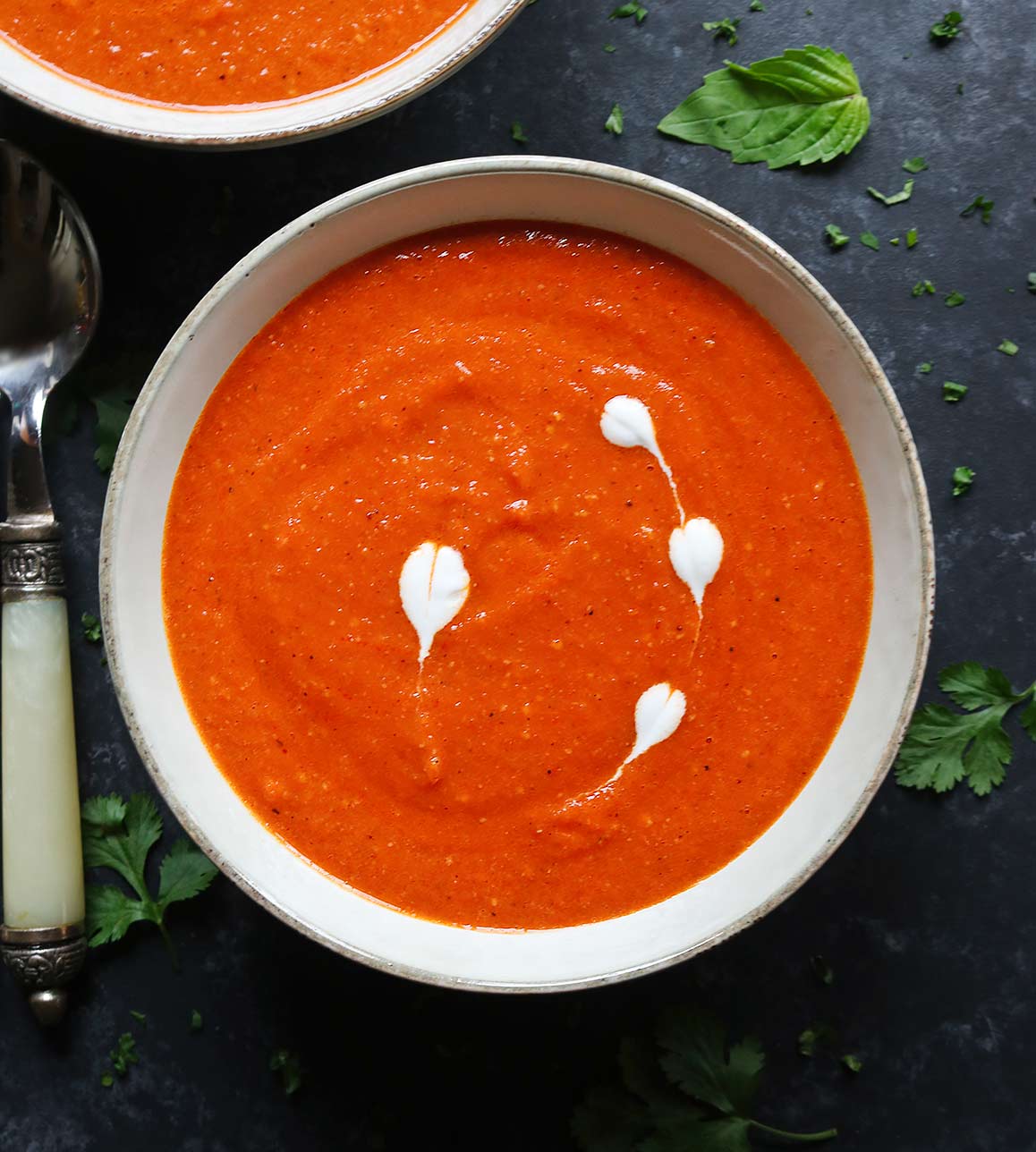 Close up of a bowl of Sheet Pan Roasted Red Pepper Tomato Soup with a spoon.