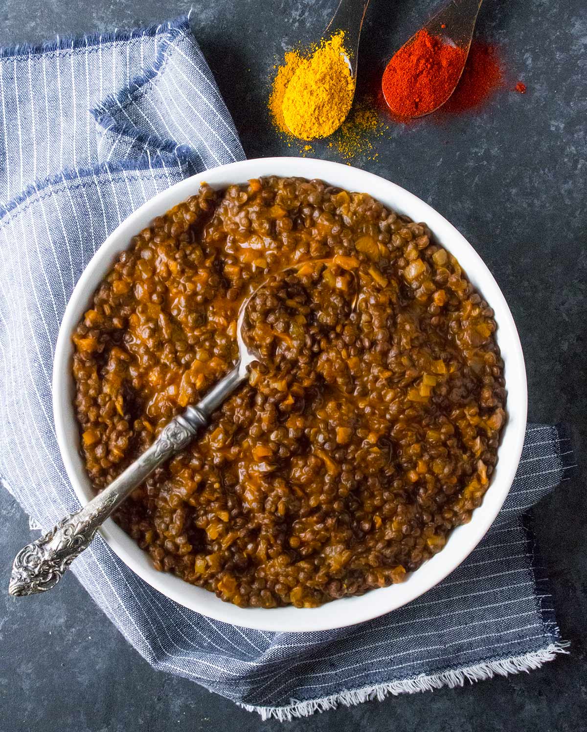 Overhead view of Vegetarian Curried Lentil Stew in a white bowl with a spoon.