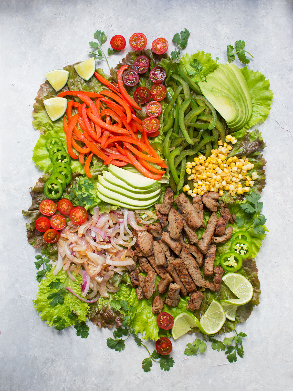 Ingredients for the Beef Fajita Salad spread out on a board.