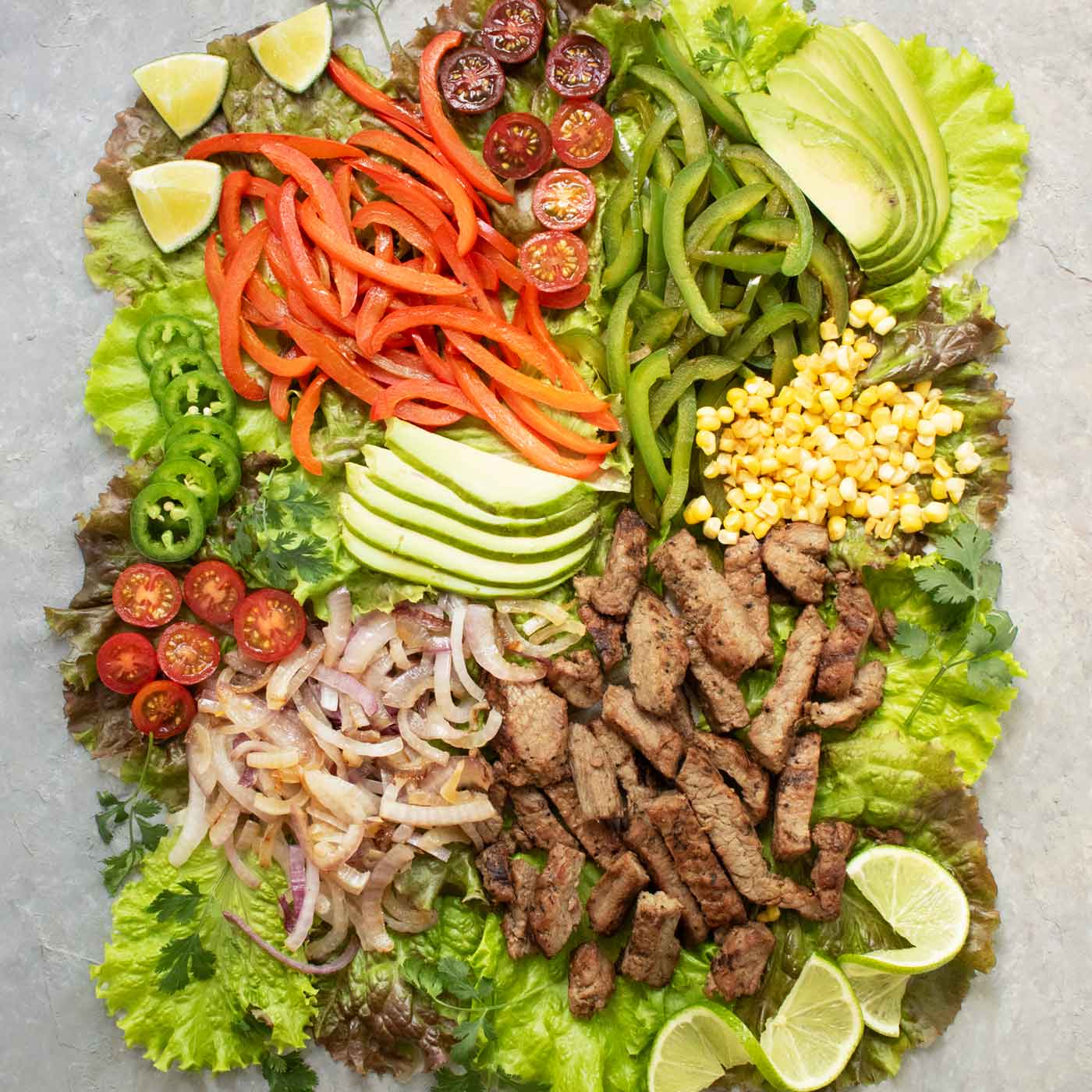 Overhead view of fajita salad ingredients arranged on a board.