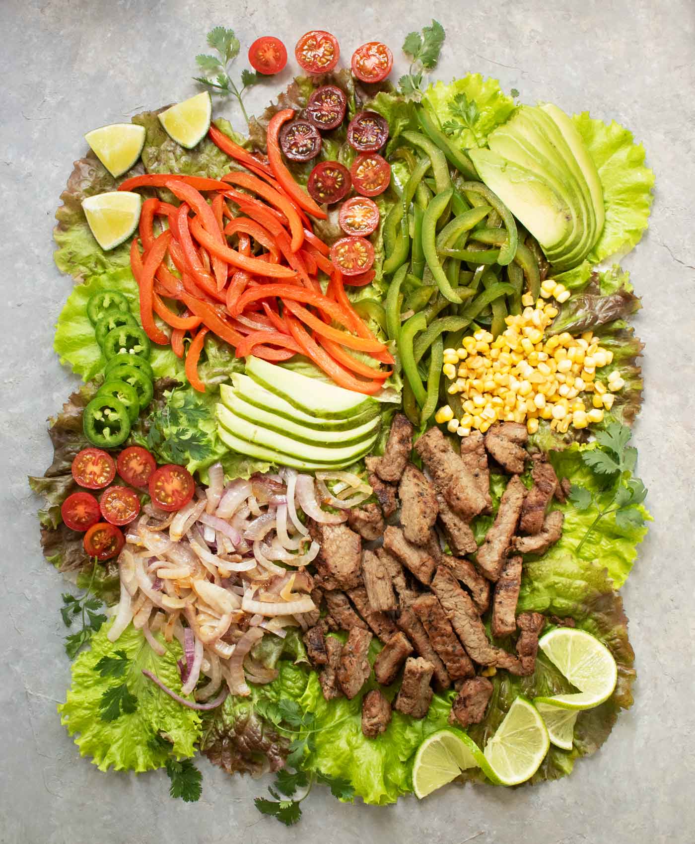 Ingredients for Steak Fajita Salad arranged on a board.