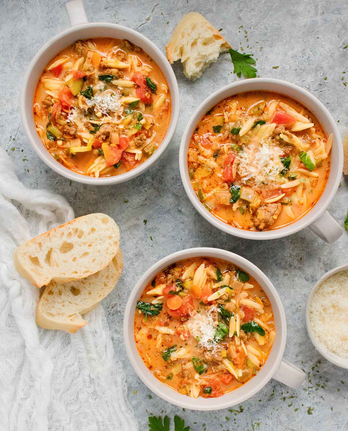 Overhead view of three bowls of Italian Sausage Orzo Soup.