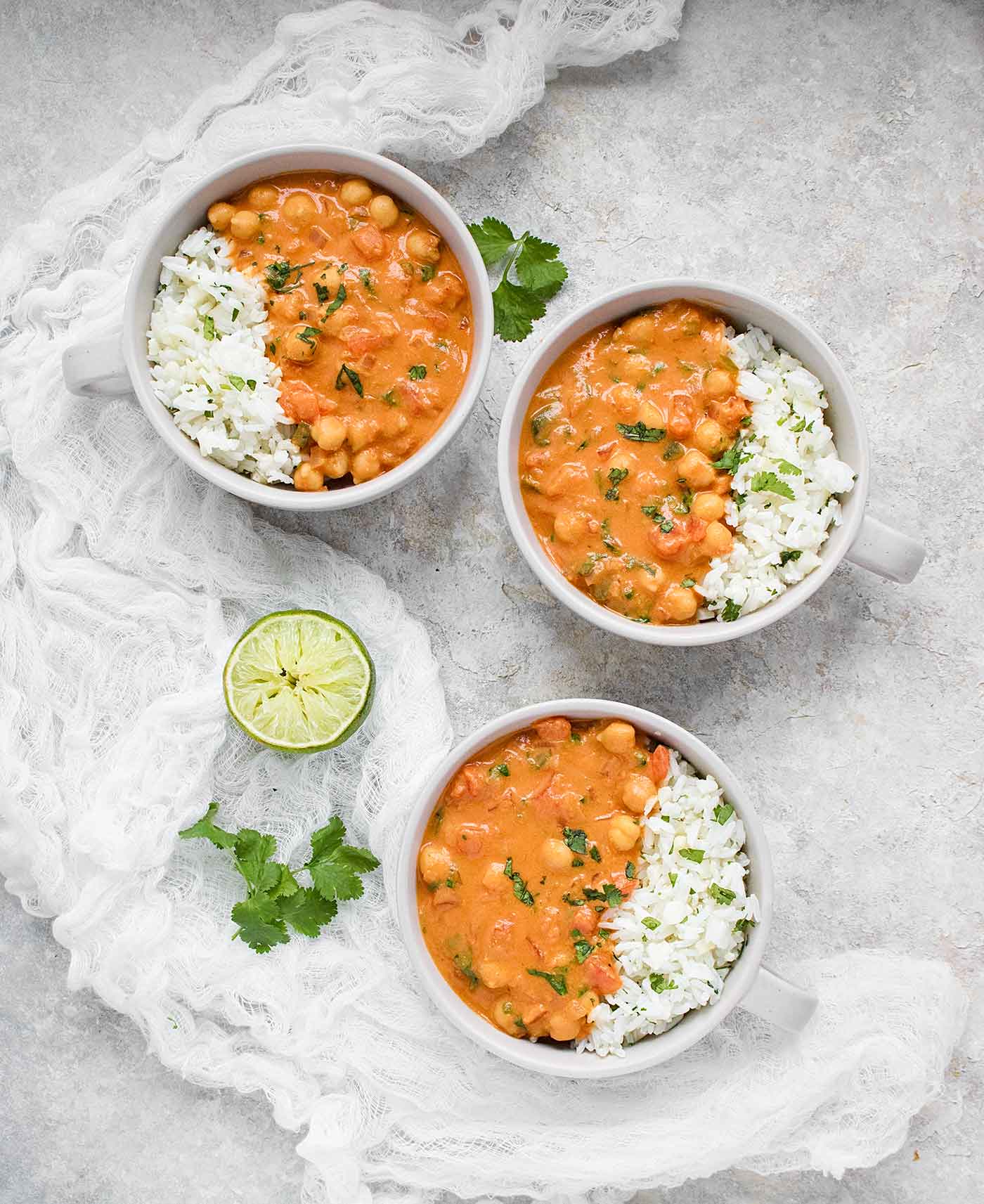 Three bowls of chickpea peanut stew served with cauliflower rice blend