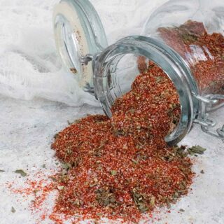 Creole Seasoning spilling out of a glass spice jar