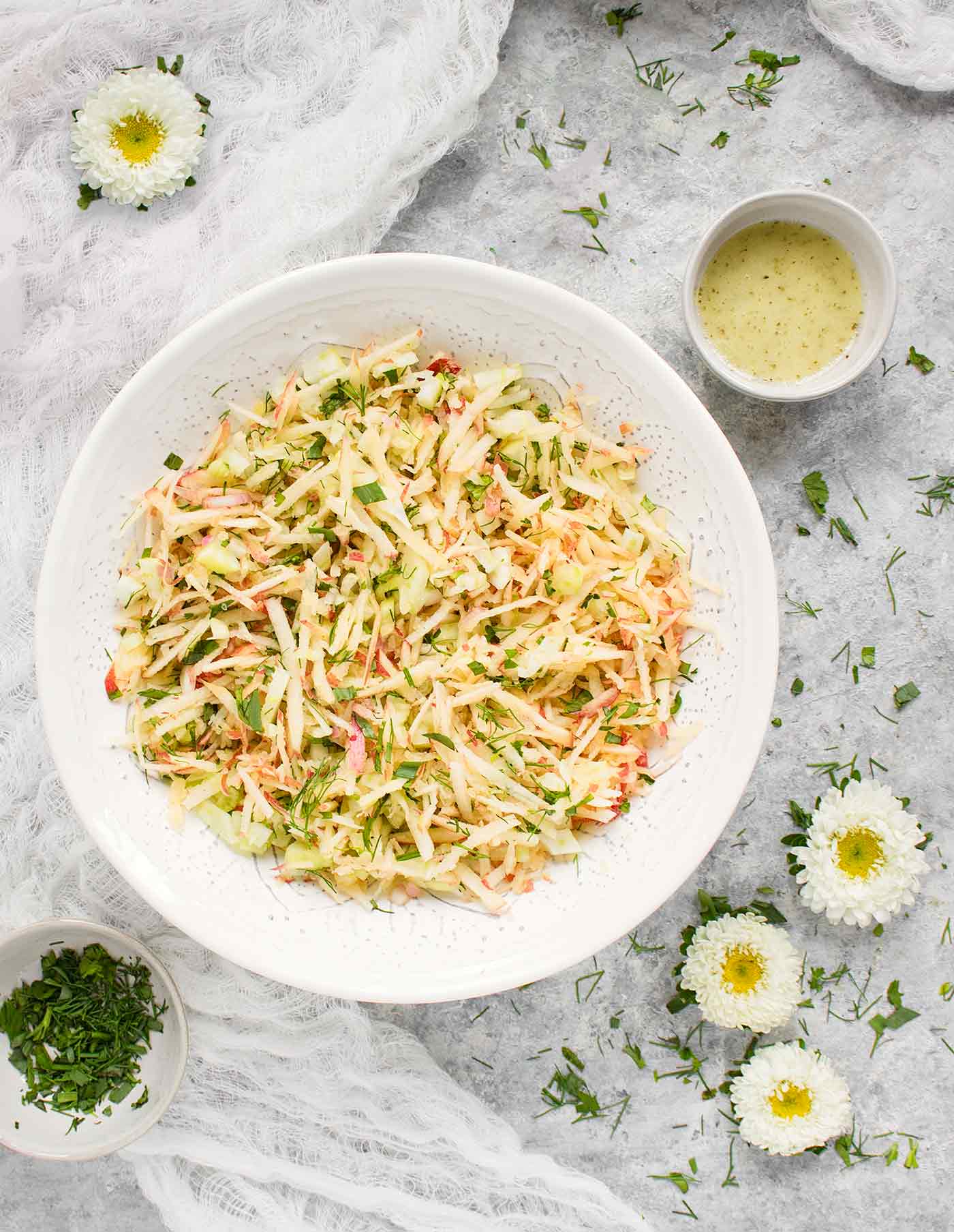 Apple Fennel Slaw in a white serving bowl with dressing on the side