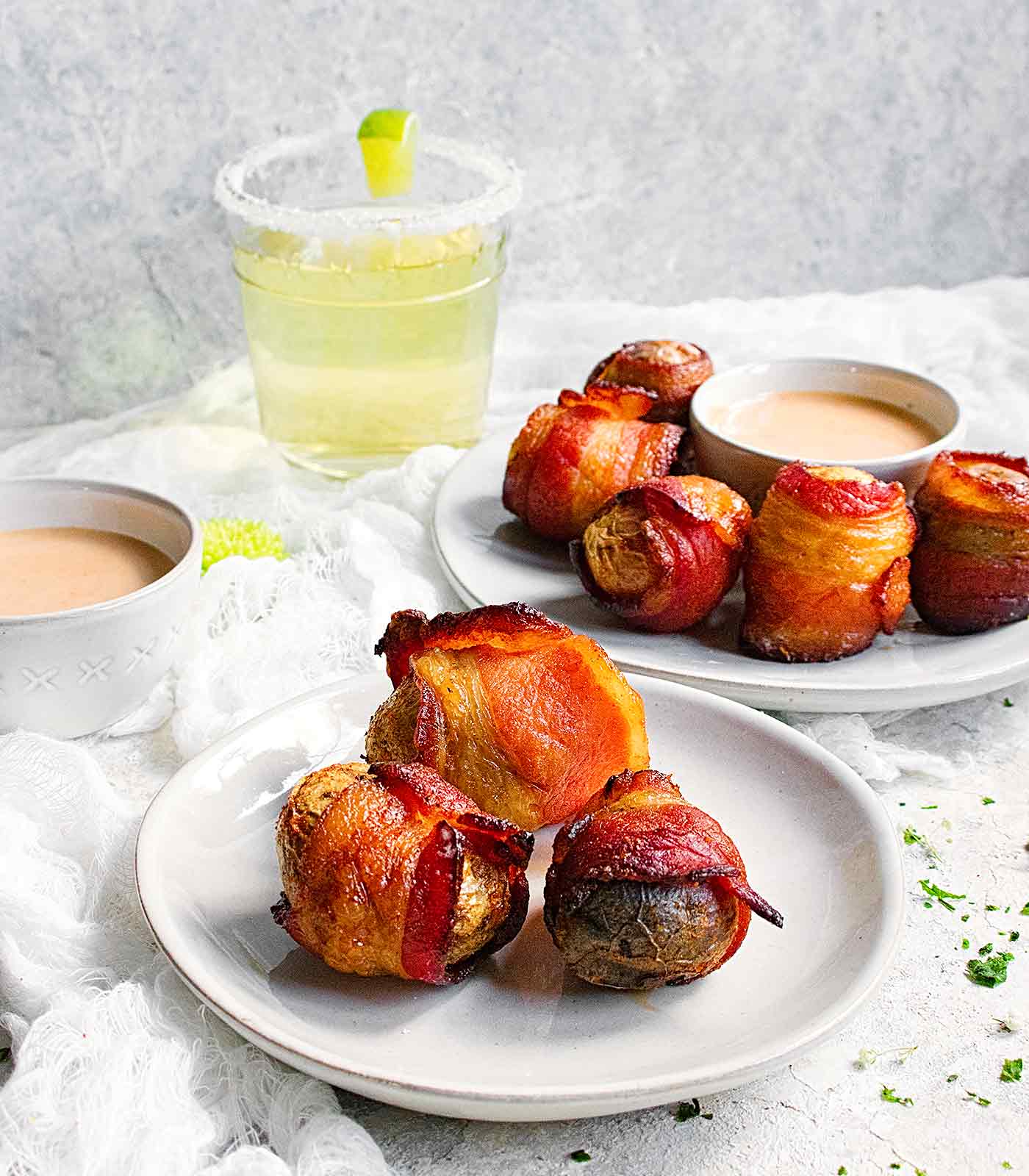 Bacon wrapped potatoes served on individual plates with dipping sauce on the side