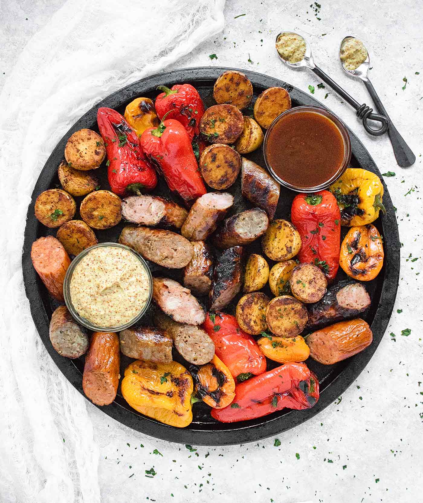 Grilled sausages, mini bell peppers, and baby potatoes on a platter