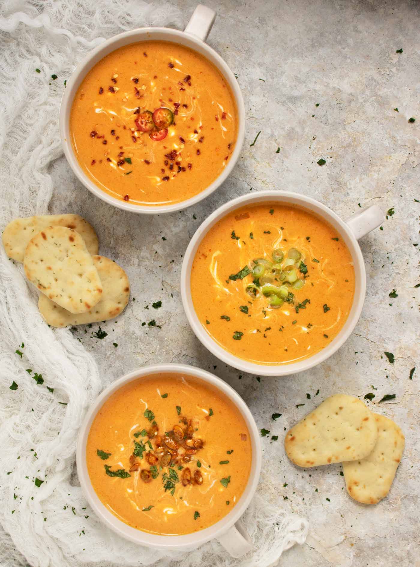 Tall vertical image of three bowls of Thai Pumpkin Soup on a gray board.