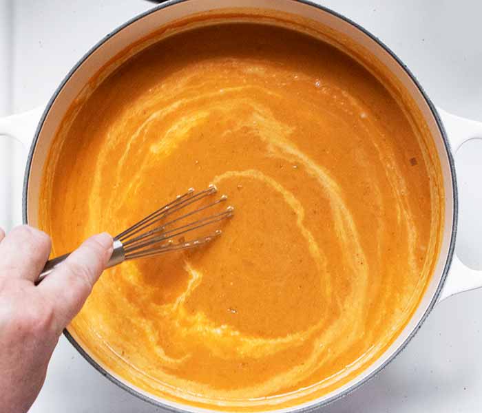 Finishing the soup by stirring in the coconut milk.