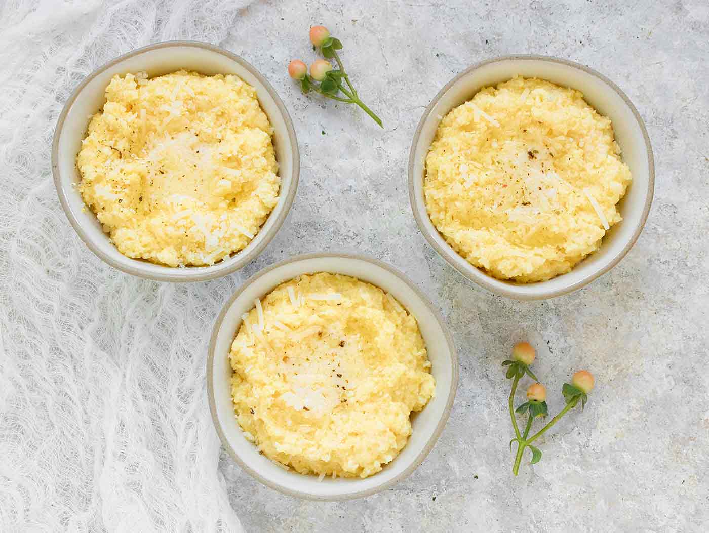 Three bowls of creamy, buttery cheese grits.