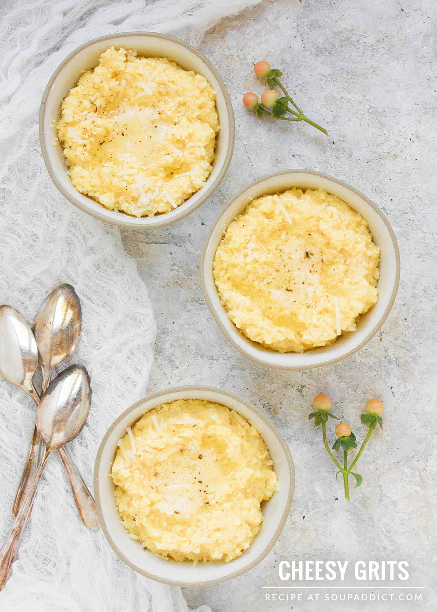 Three small bowls of cheese grits, with spoons on the side