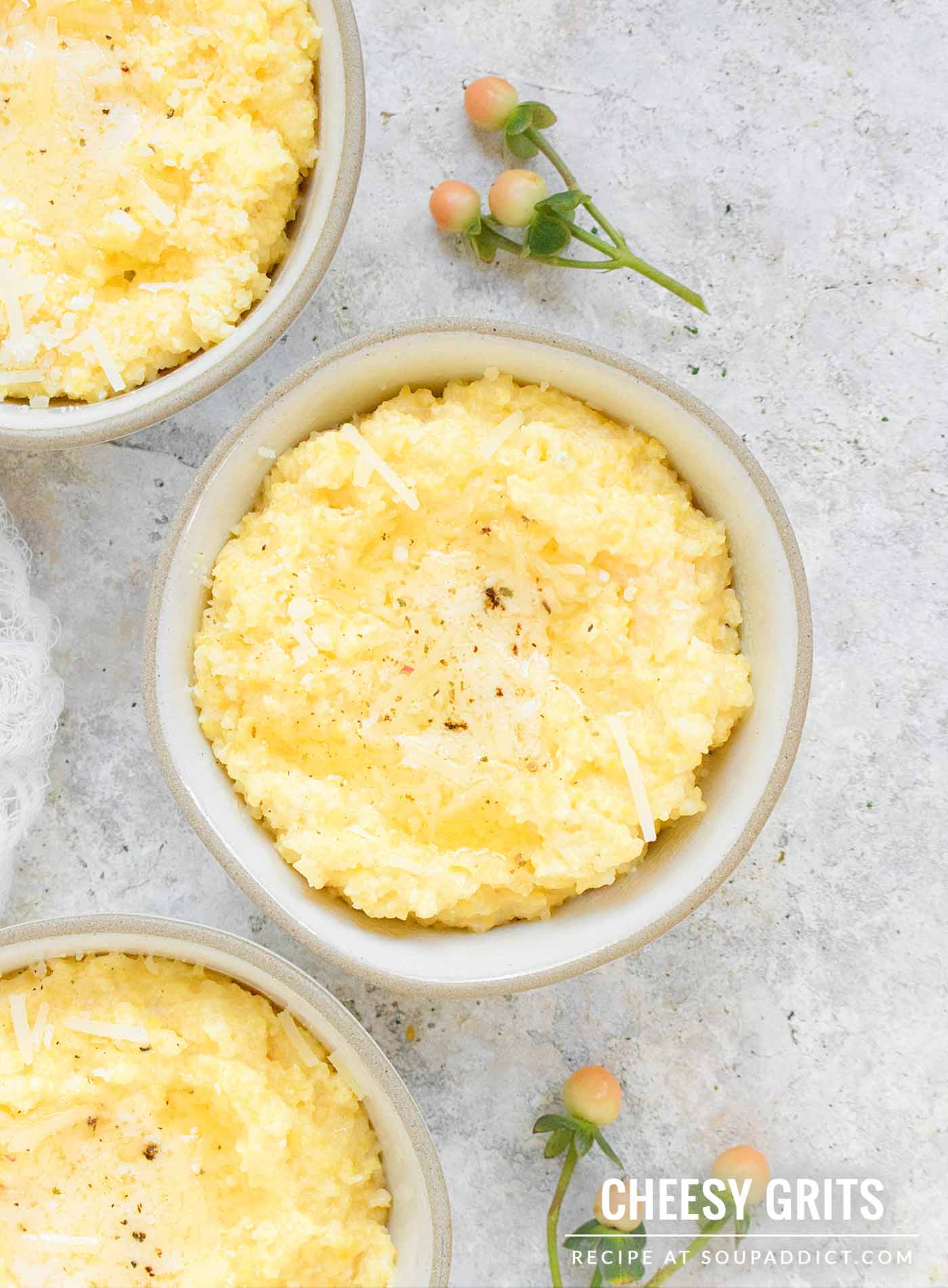 Close-up of a small bowl of cheese grits topped with melted butter and a cracking of black pepper