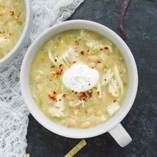 One bowl of White Chicken Chili topped with sour cream and red pepper flakes