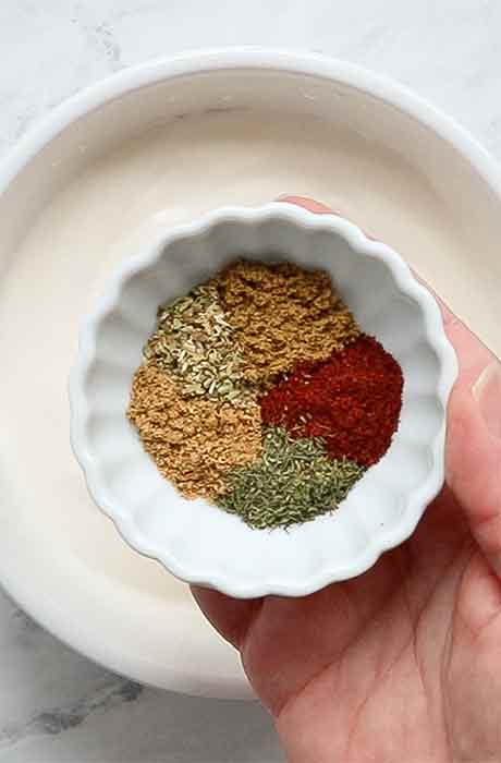 Herbs and spices in a pinch bowl, ready to add to the creamy base.