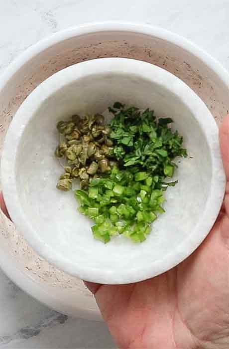 Chile peppers, capers, and fresh cilantro in a pinch bowl, ready to add to the sauce.