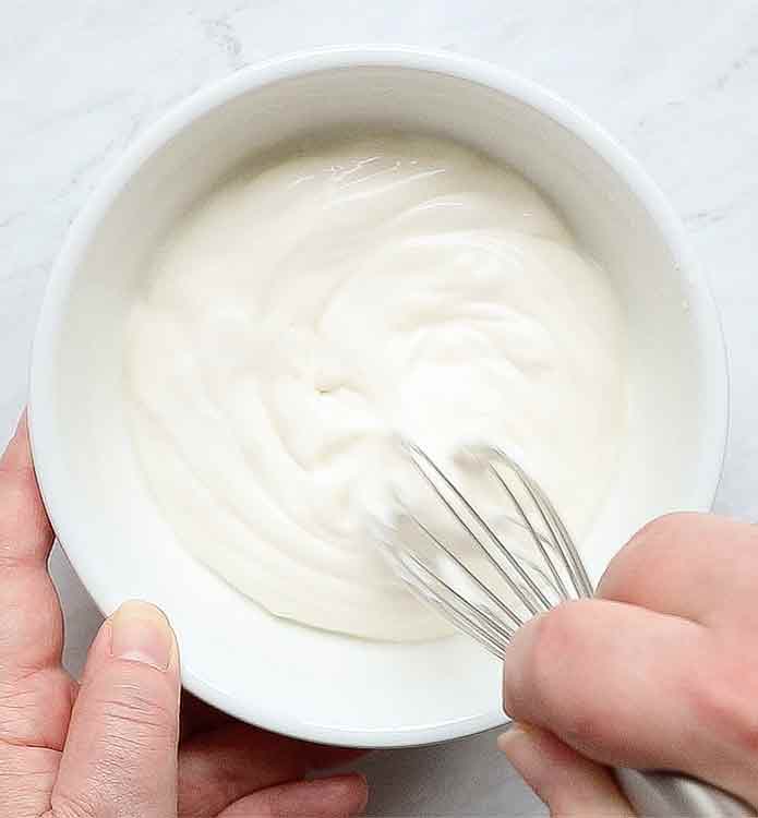 Whisking the mayo and sour cream until smooth.