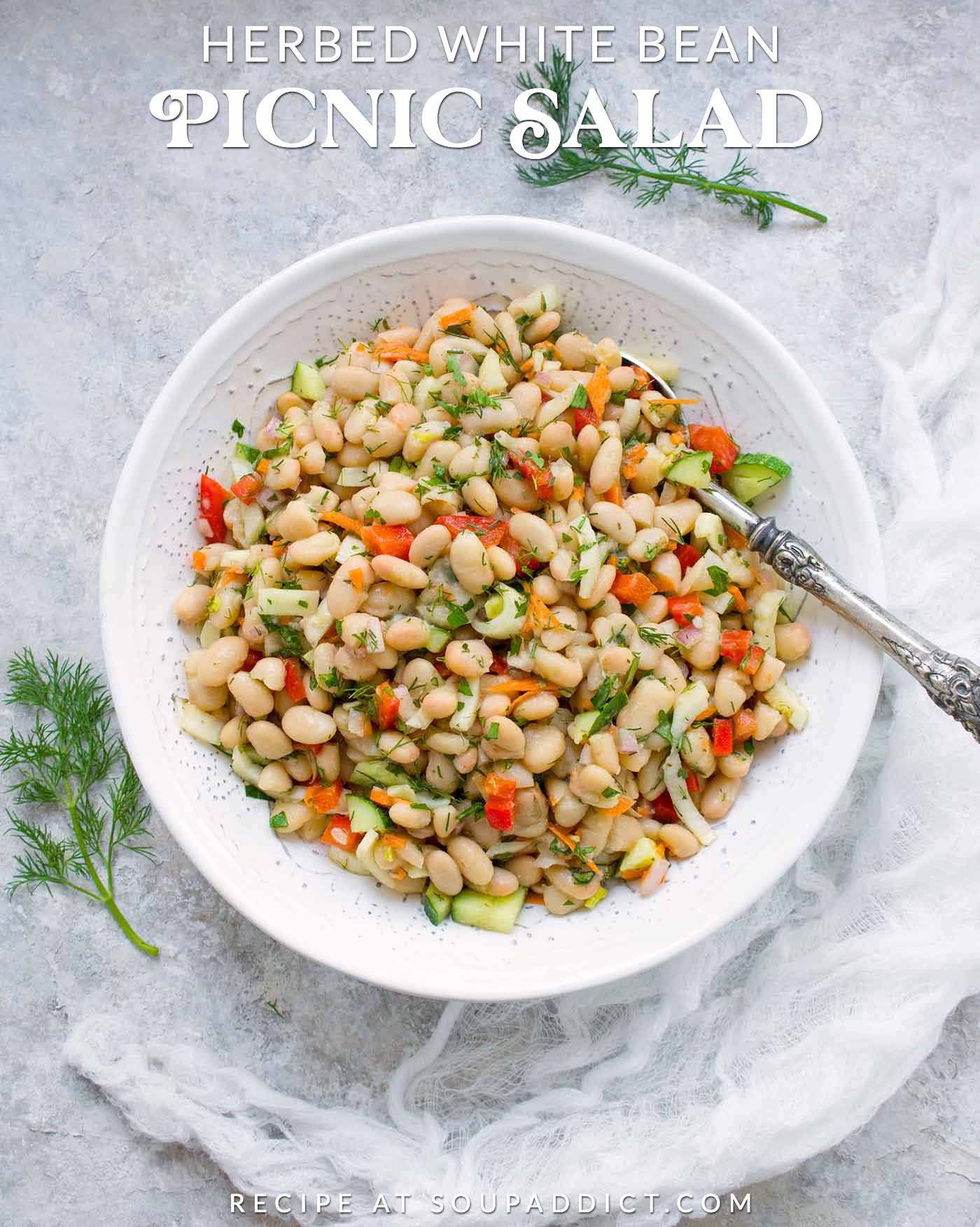 Herbed White Bean Picnic Salad in a white serving bowl with a spoon